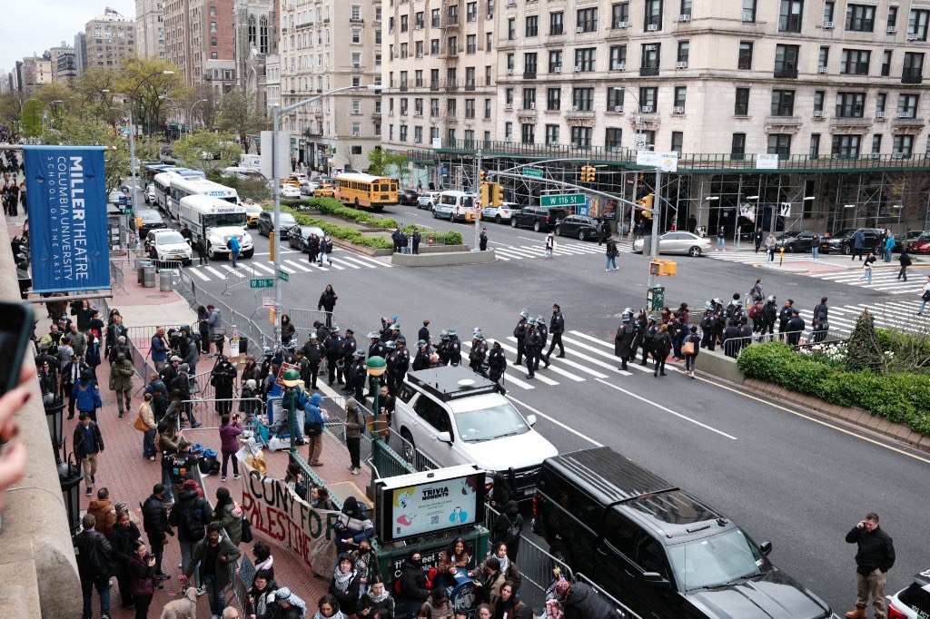 NYPD officers march across the intersection at Broadway and W 116th Street outside Columbia University