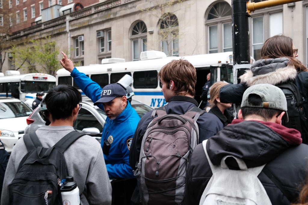 An NYPD community affairs officer directs pedestrians near police buses