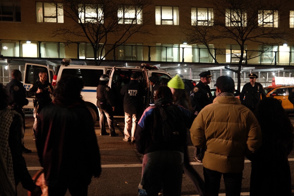 NYPD officers near a police van at night outside Columbia